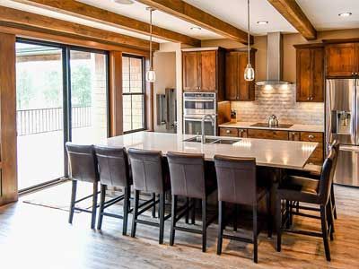 Spacious kitchen with island seating, wooden beams, and sliding door to a deck.