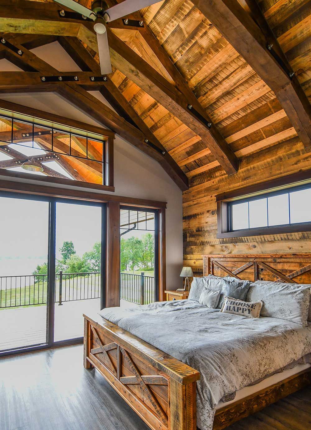 Rustic bedroom with wooden ceiling, bed, and open doors to a balcony.
