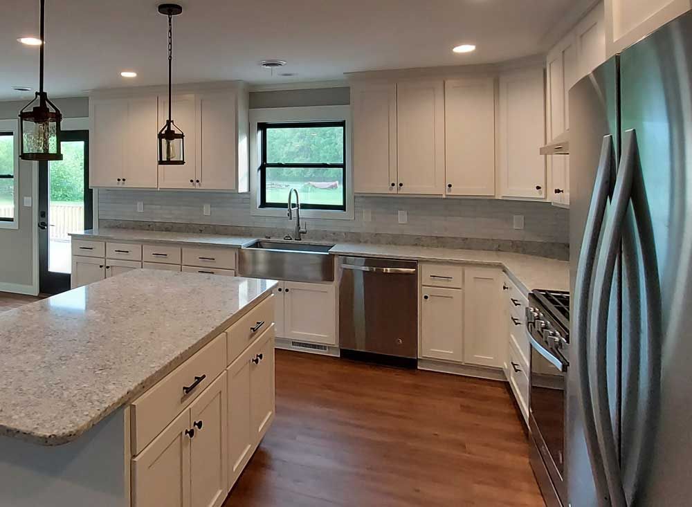 Modern kitchen with white cabinets, stainless steel appliances, and a granite countertop island.
