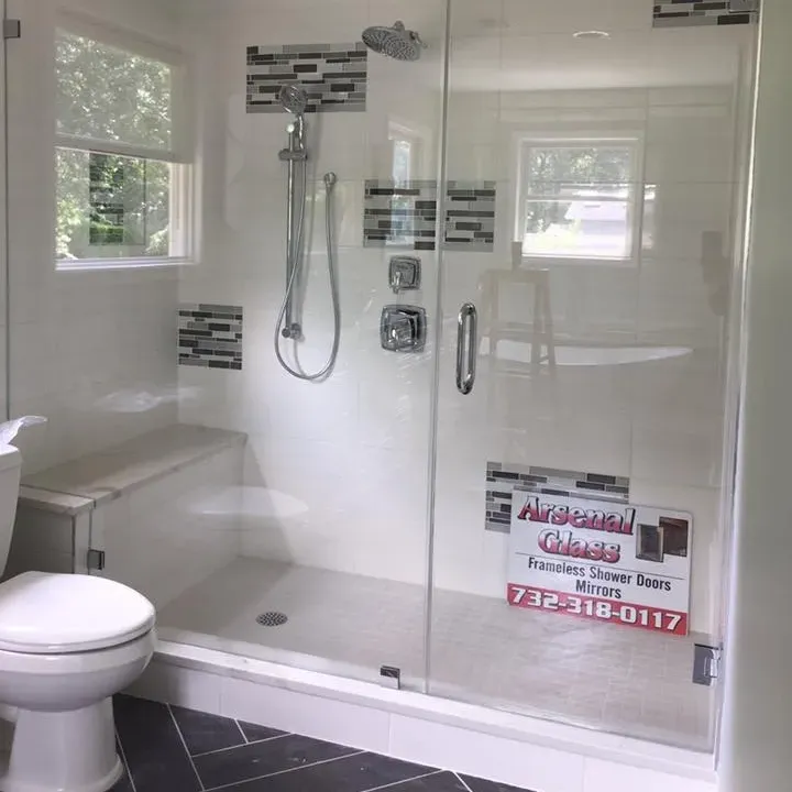 Custom frameless glass shower enclosure featuring a built-in bench, expertly installed in a modern bathroom by Arsenal Glass in New Jersey.