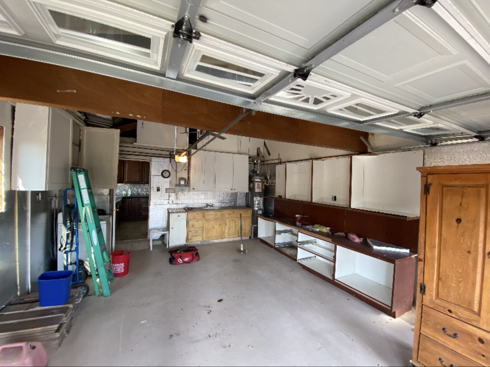 Garage interior with cabinets, tools, and a ladder. The space appears under construction.