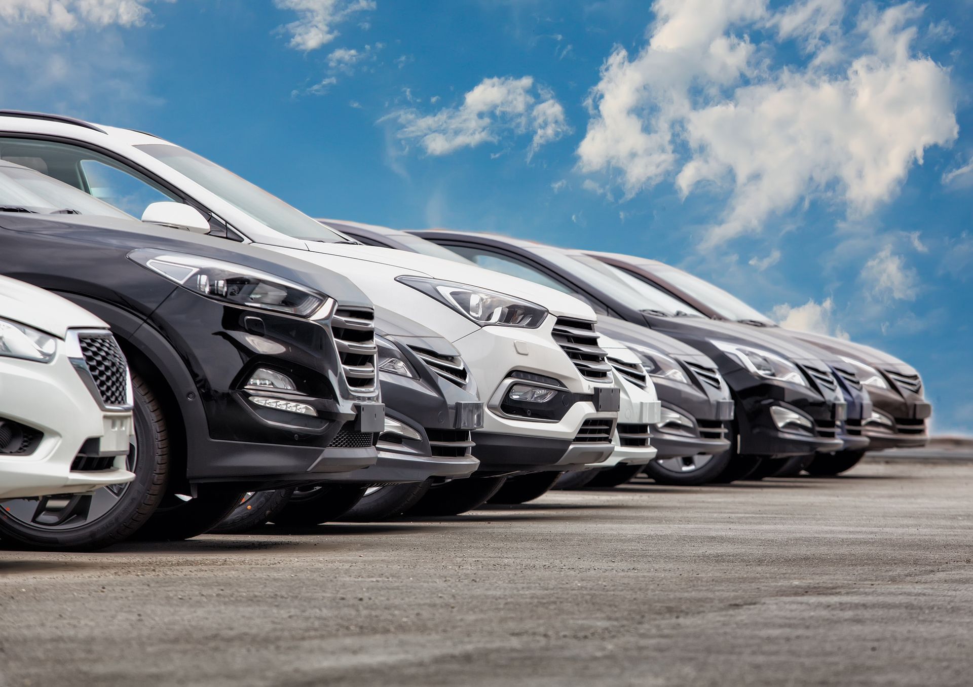 A row of cars are parked in a parking lot.