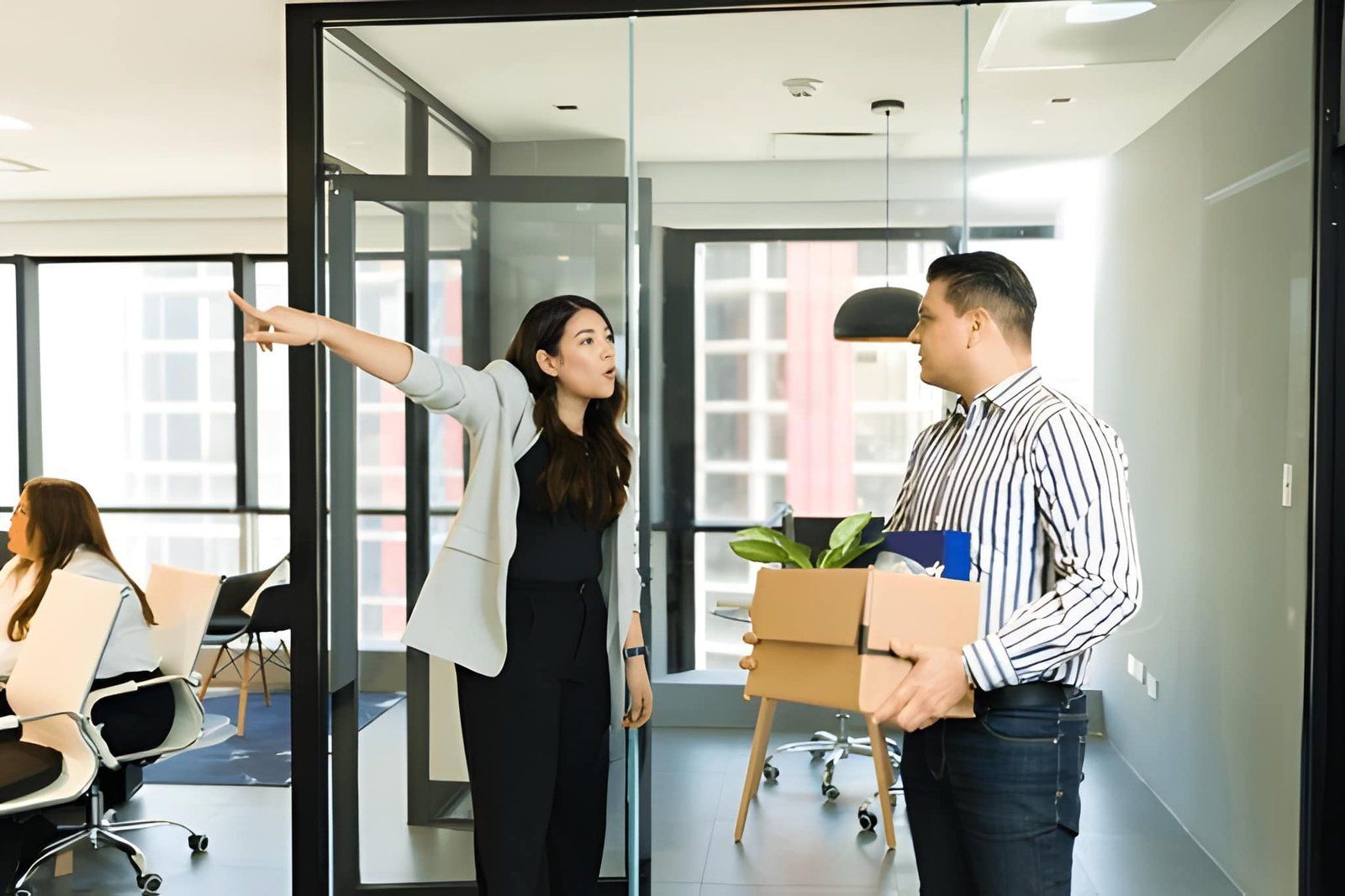 A Person Gestures Toward a Doorway While Another Holds a Box — Australian Employee Lawyers in Broadbeach Waters, QLD