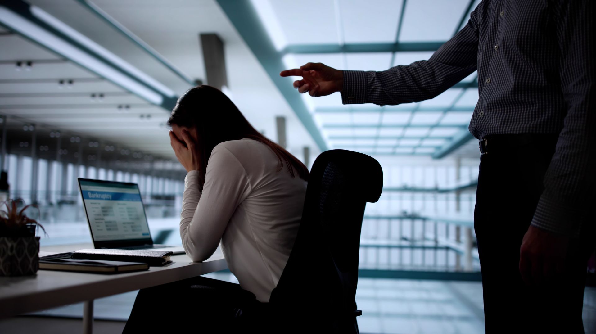 A Person Sits at a Desk While Another Person Points at Them — Australian Employee Lawyers in Broadbeach Waters, QLD