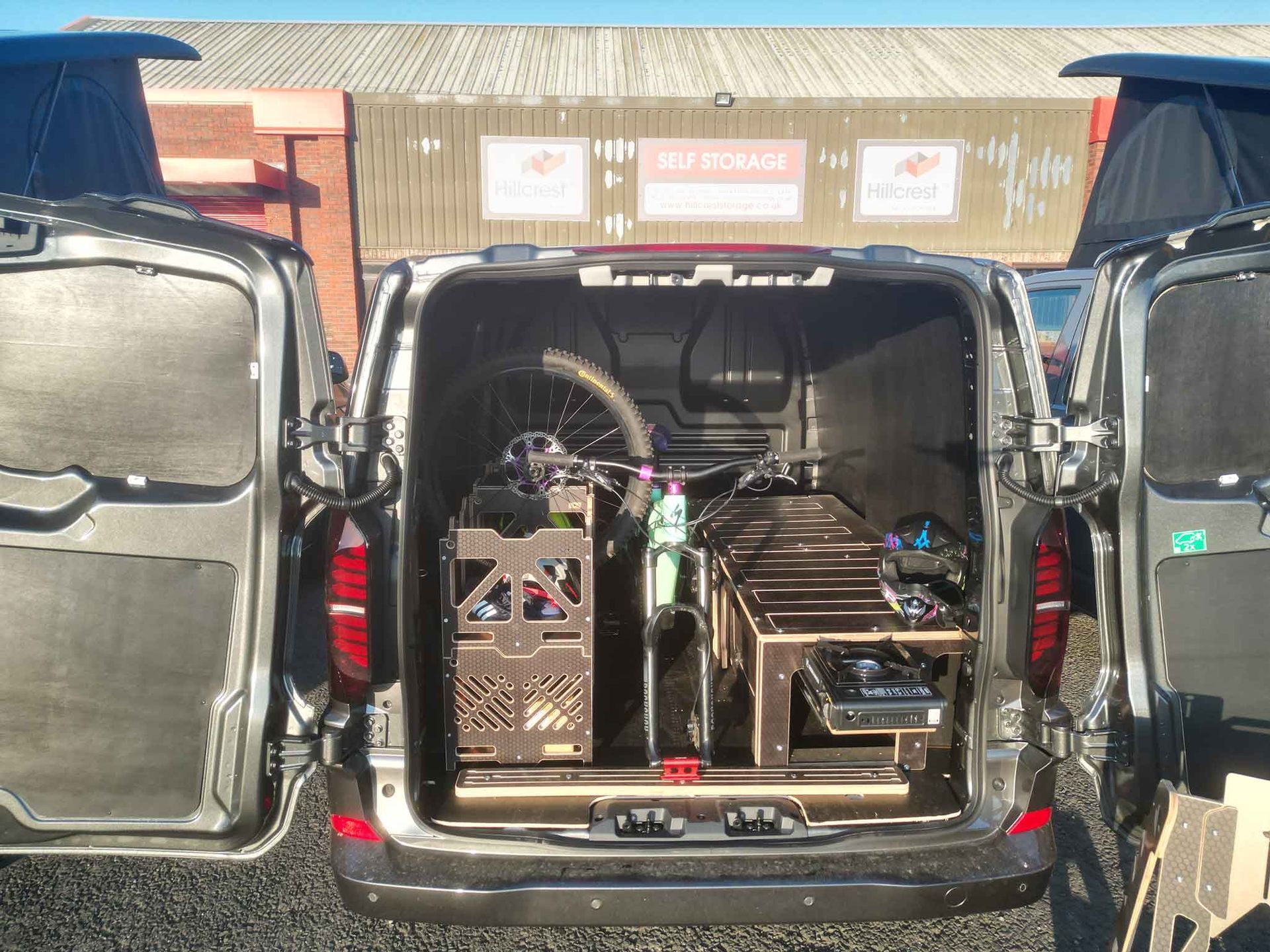 Open black van with equipment cases loaded in the back, flanked by two other open vans outdoors