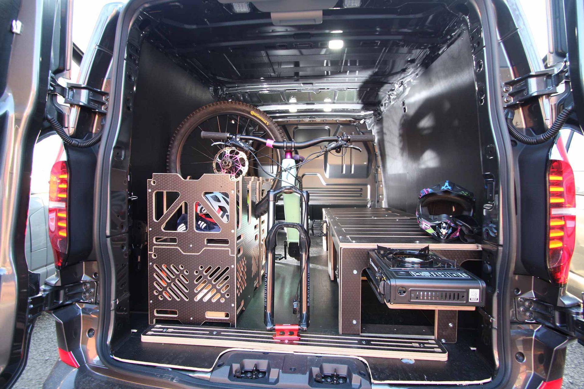 Open van interior with a custom-built machine or equipment setup and a red bottle on the floor.