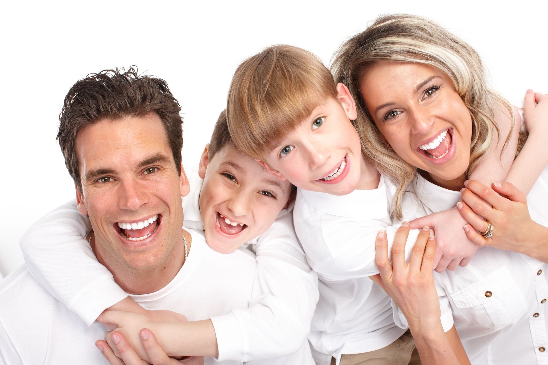 Two adults and two children stand close in matching white shirts. Two adults and two children stand close in matching white shirts.