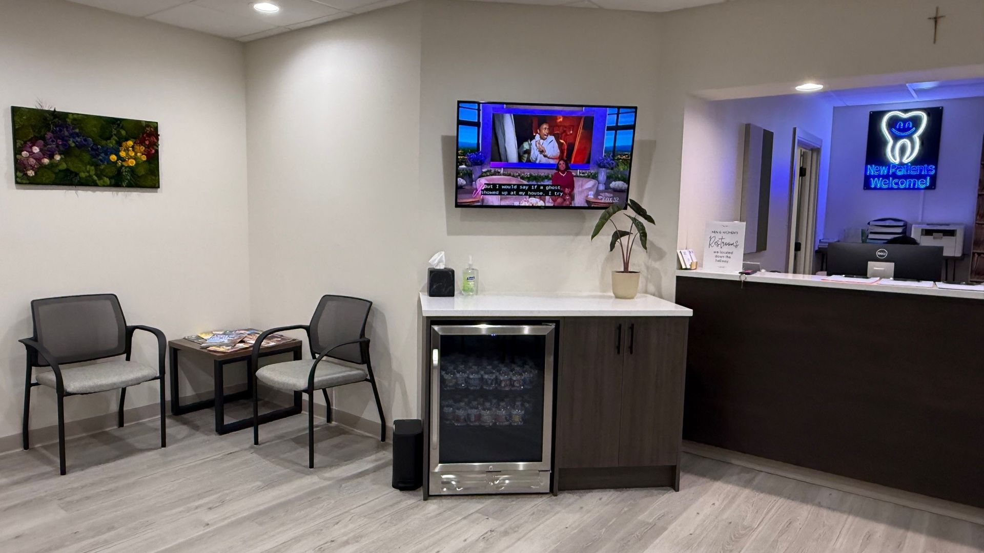 Dental office waiting room with chairs, TV, and reception desk.