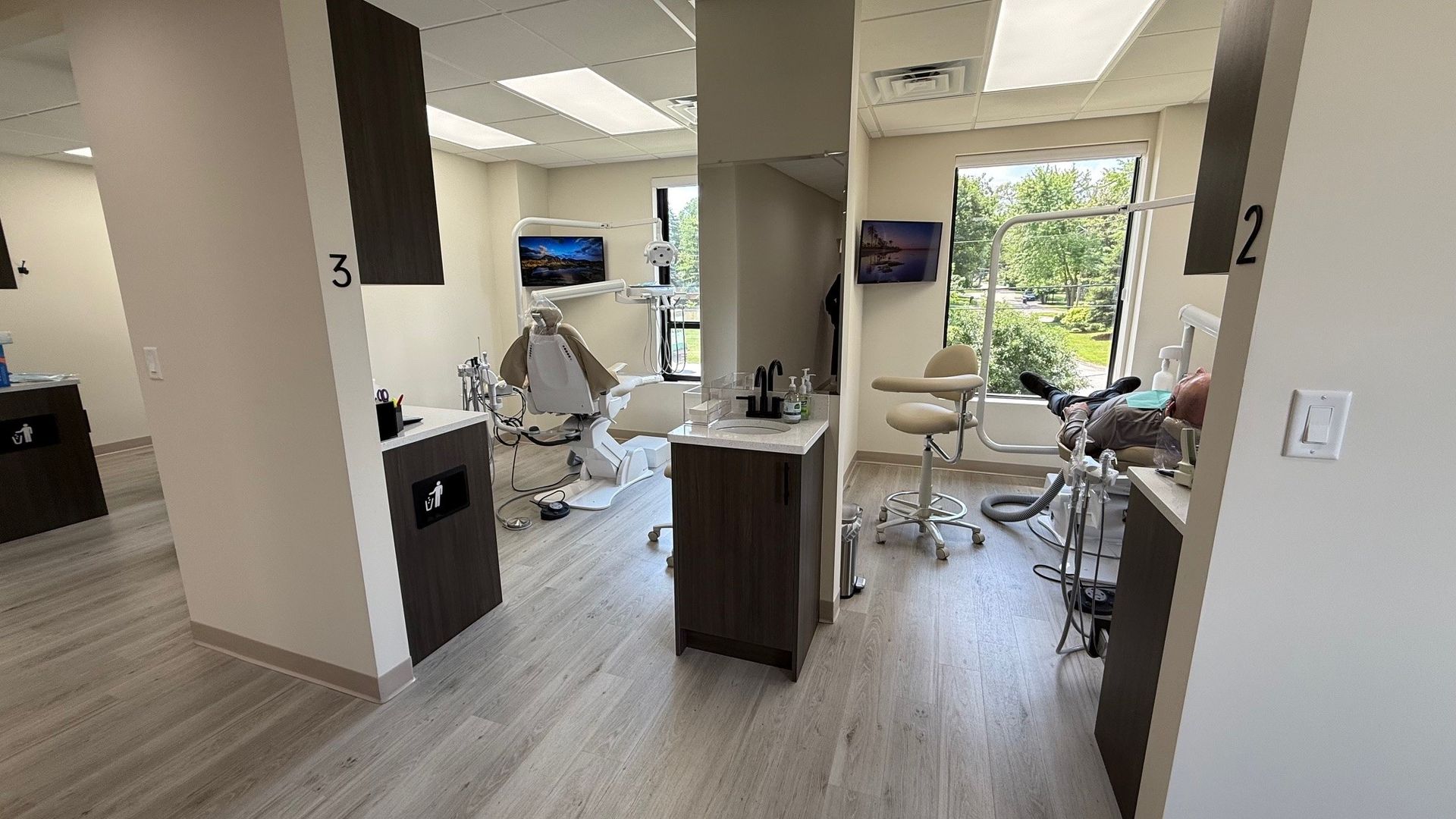 Dental office exam rooms with chairs, equipment, and windows.