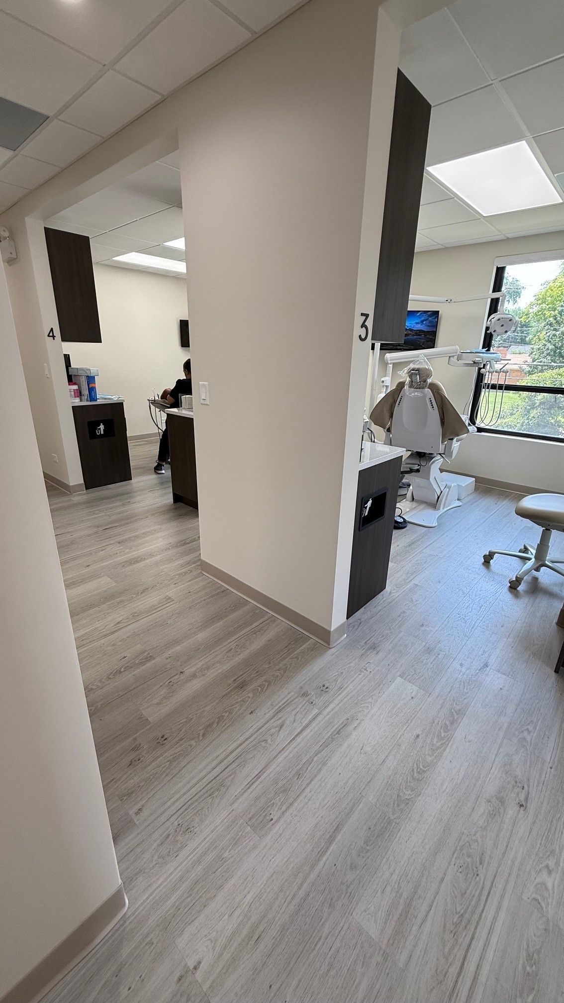 Dental office interior with white walls, gray floor, dental chair, and equipment.
