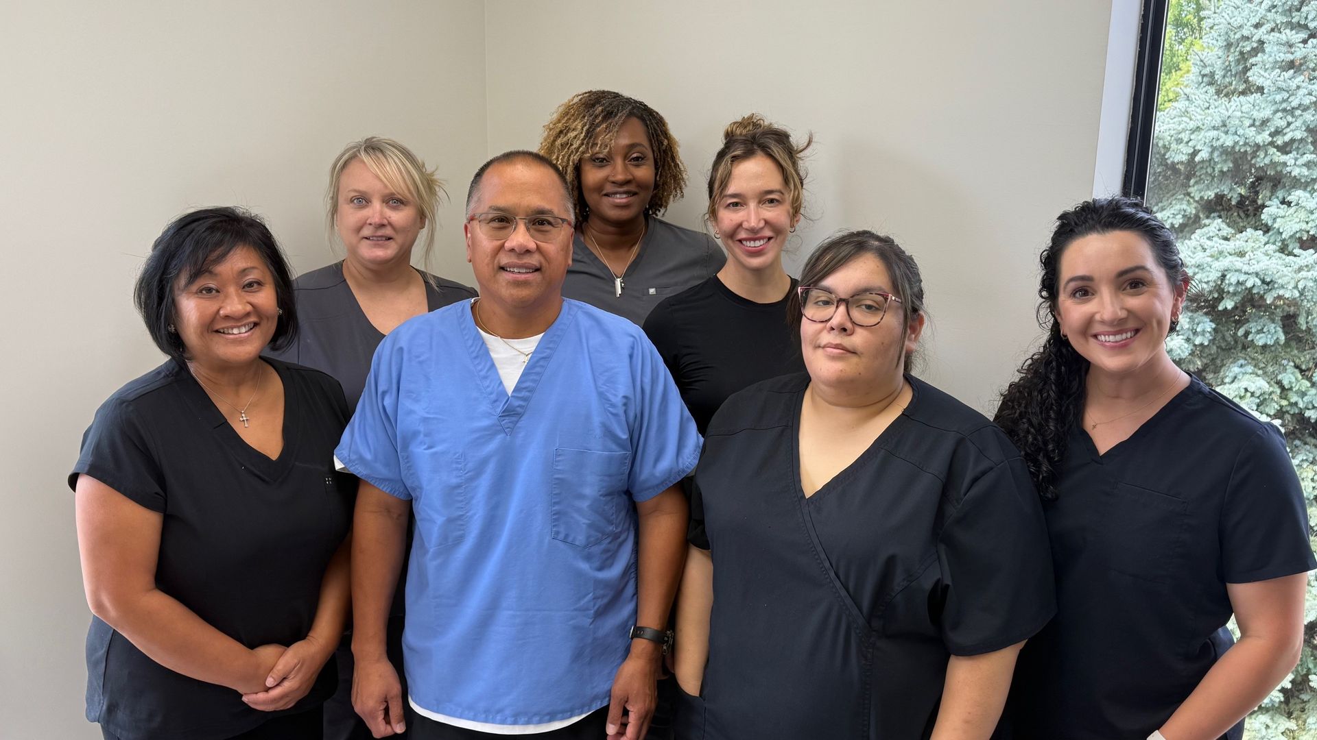Group of healthcare professionals, standing together, smiling, in an office setting.