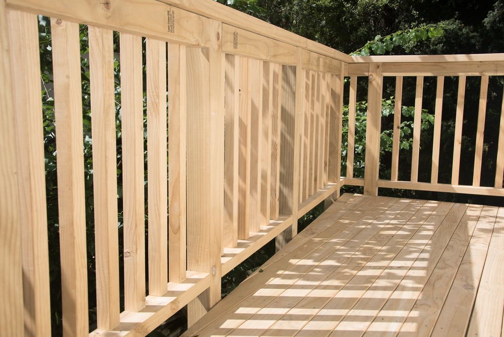 A Wooden Deck With a Wooden Railing and Trees in the Backgroun — Better Built Patios & Decking in Kingscliff, NSW