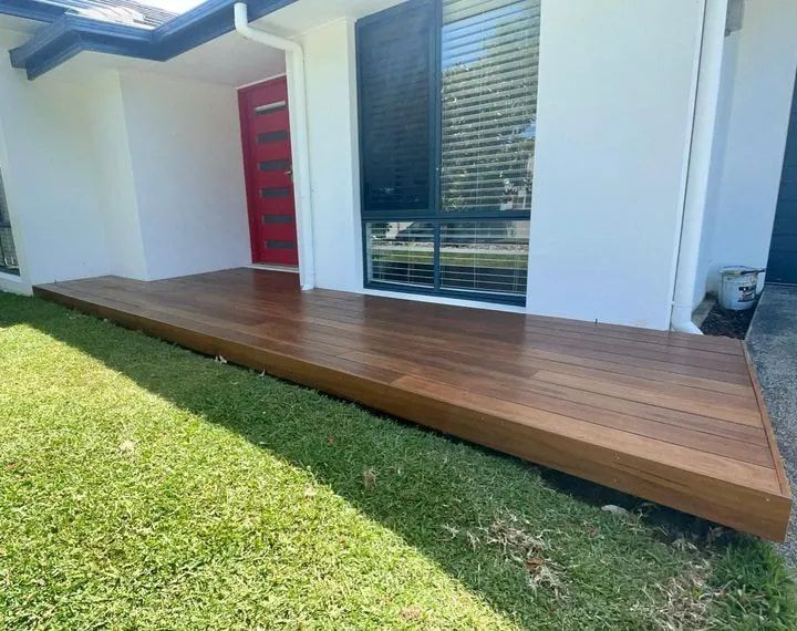 A Wooden Deck is in Front of a White House With a Red Door — Better Built Patios & Decking in Wollongbar, NSW