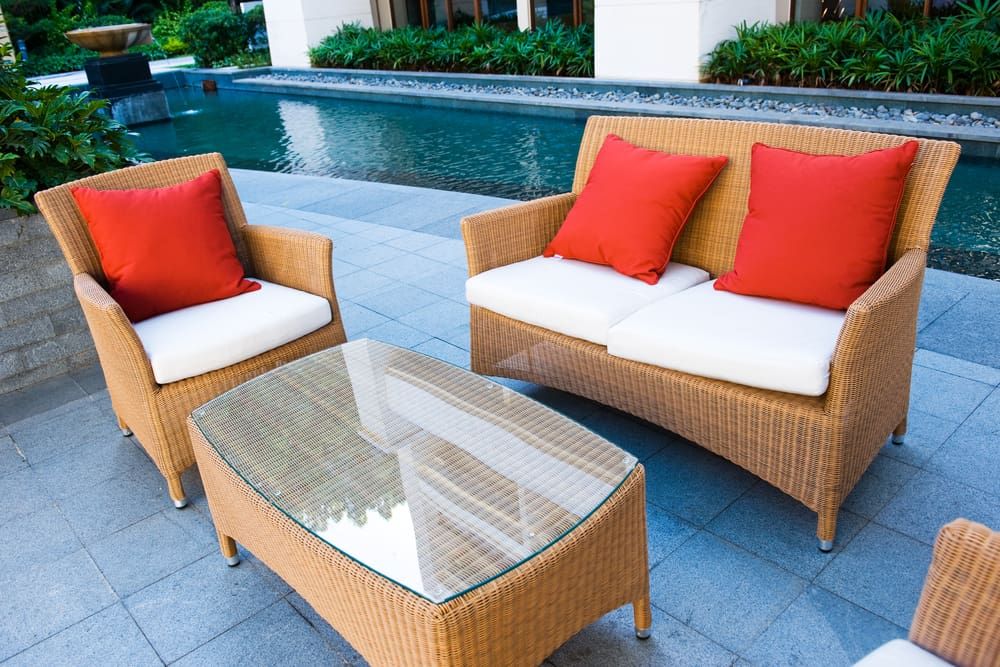 A Wicker Patio Set With Red Pillows and a Glass Table — Better Built Patios & Decking in Byron Bay, NSW