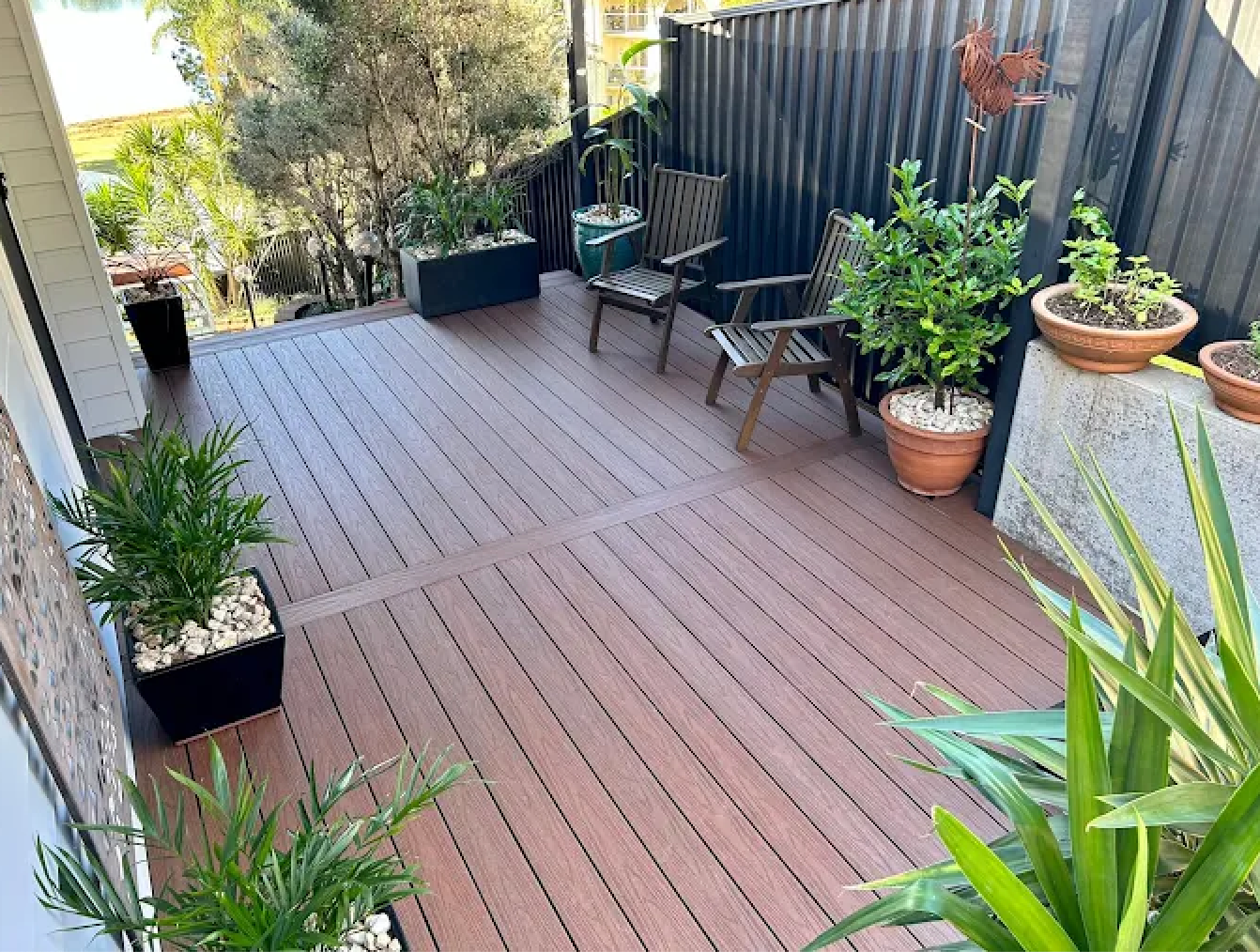 A dark wooden deck in backyard surrounded by plants — Better Built Patios & Decking in Wollongbar, NSW