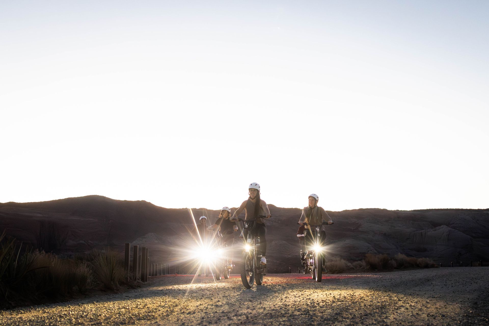 Two people are riding bikes on a dirt road at sunset.