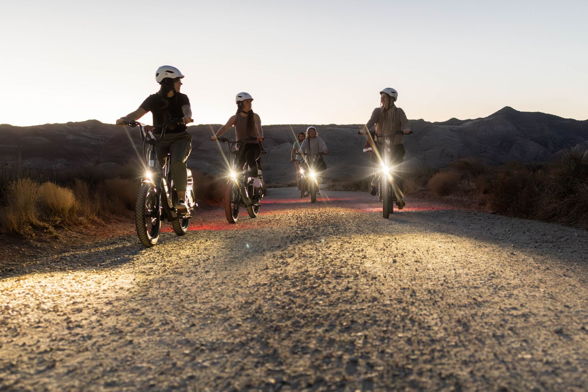 A group of people are riding bikes down a dirt road.