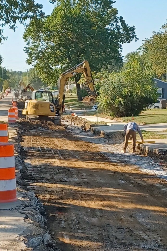 Construction workers using a jackhammer and pickaxe to remove paving stones.