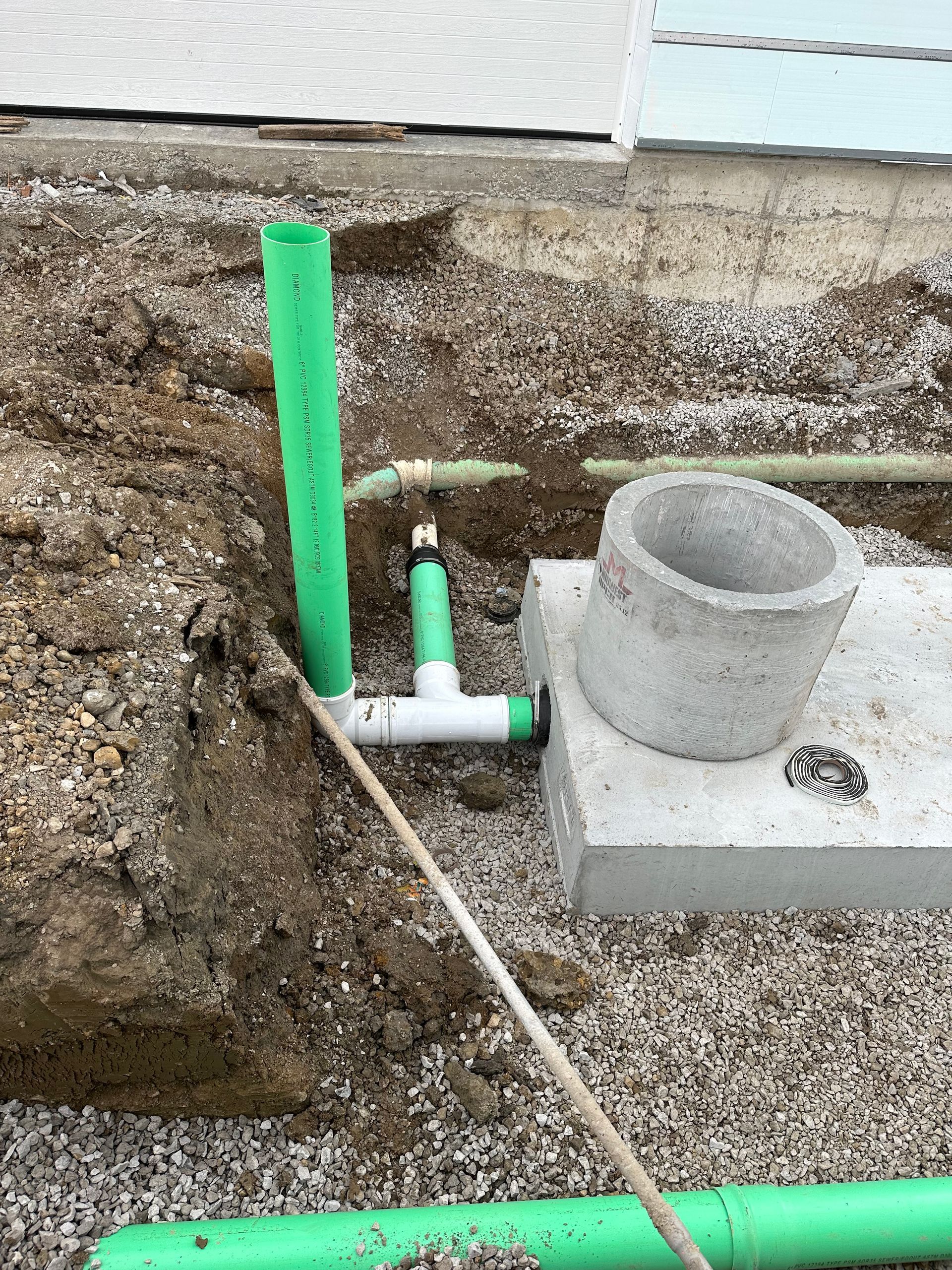 Concrete pipes being installed in a trench. Construction site with rebar visible.