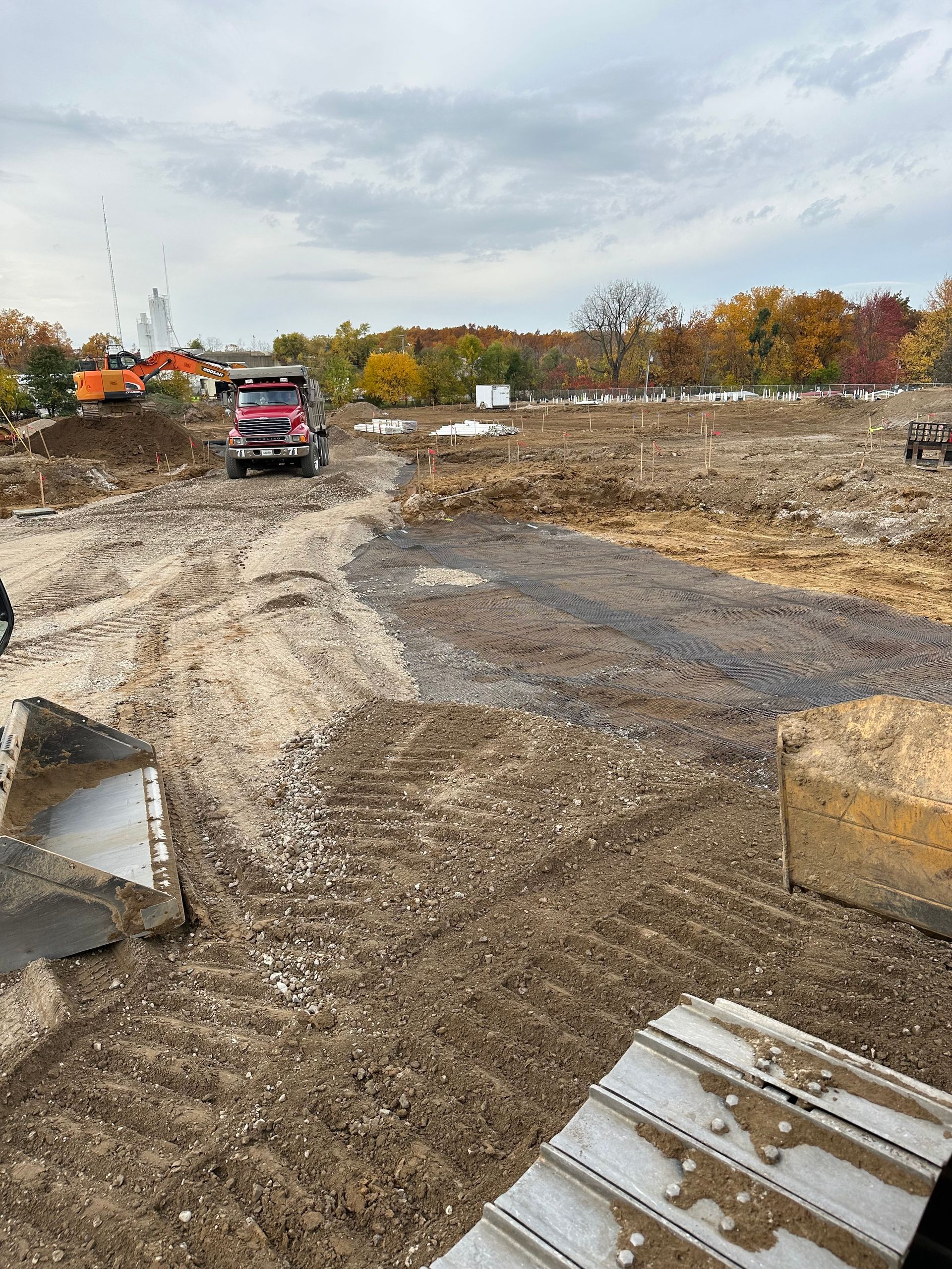 Yellow bulldozer smoothing out dirt at a construction site, creating parallel tracks.