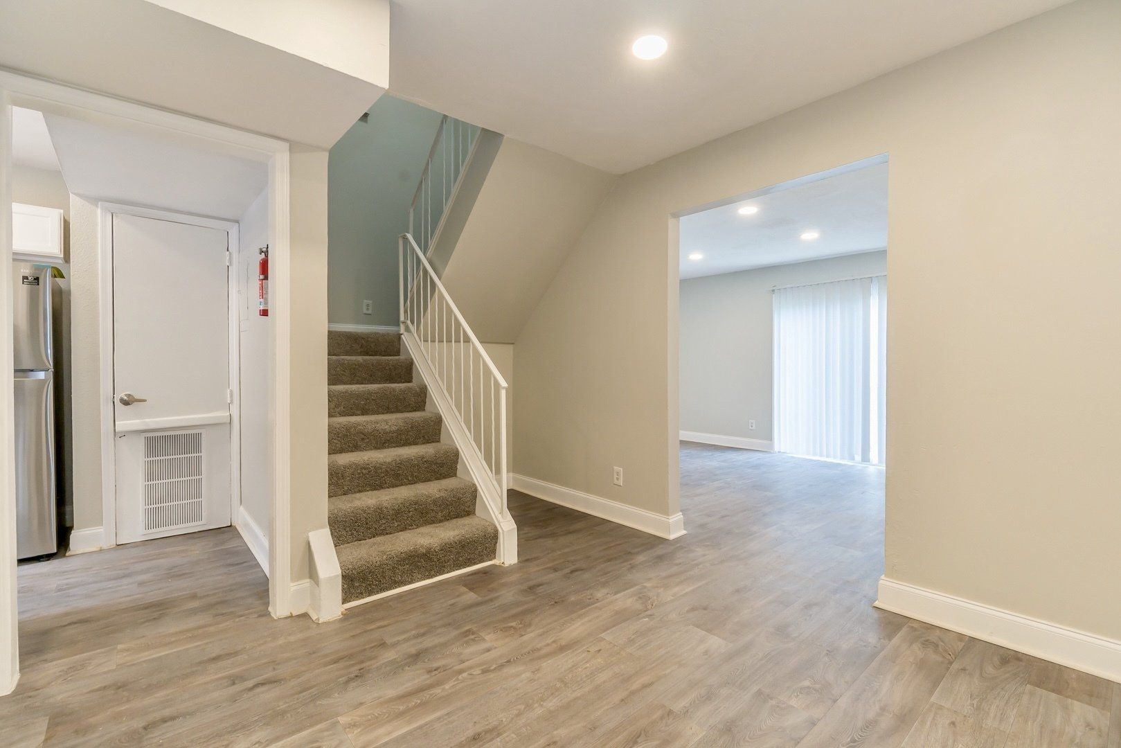 Empty modern interior with carpeted stairs, light wood floors, and open living space