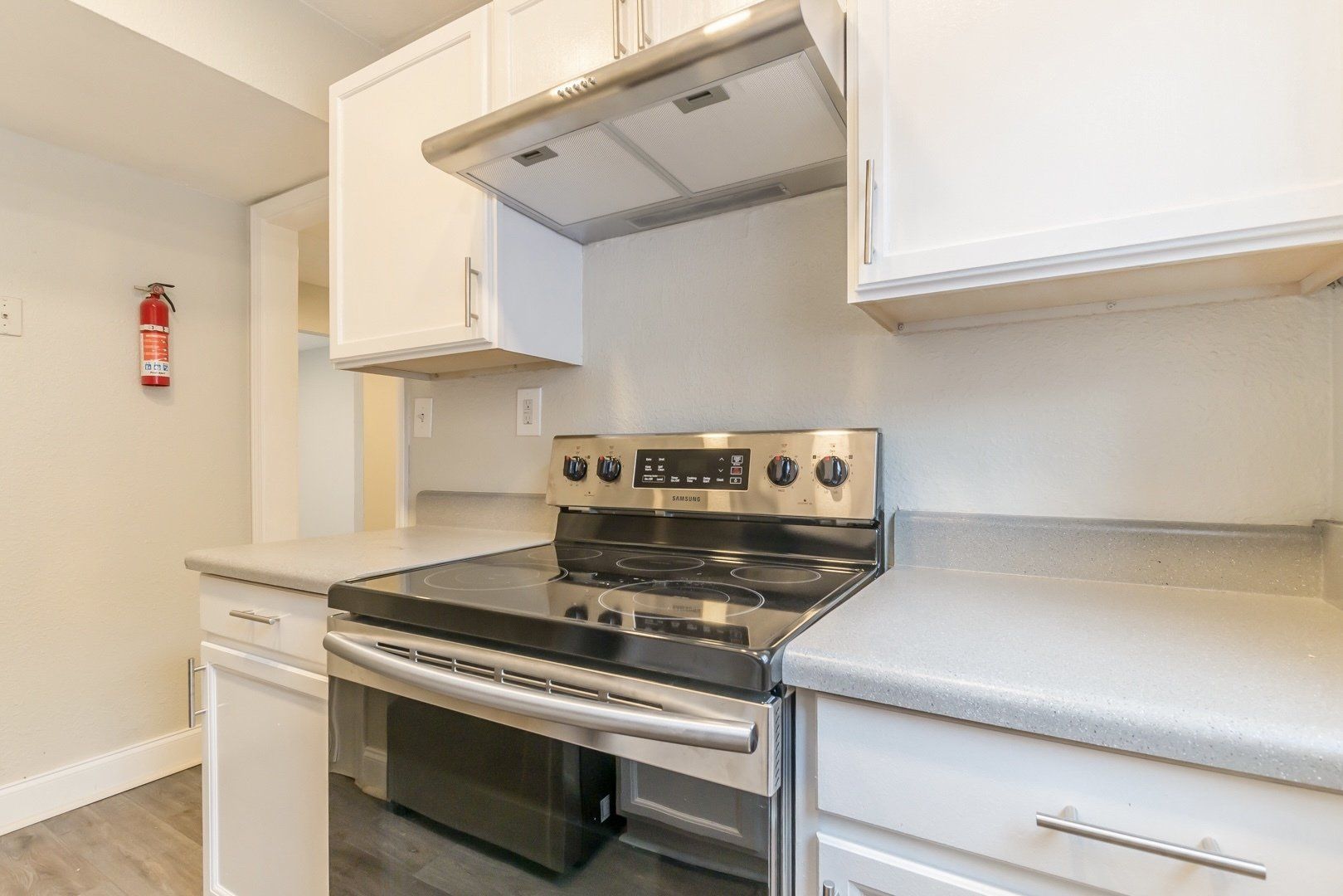 Bright kitchen with stainless steel stove, white cabinets, and light countertops
