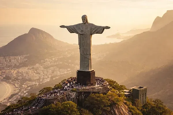 Christ the Redeemer statue overlooking Rio de Janeiro with mountains, coastline, and cityscape in the background.