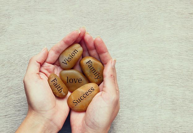 Hands cupping stones engraved with vision, purpose, love, success, and family