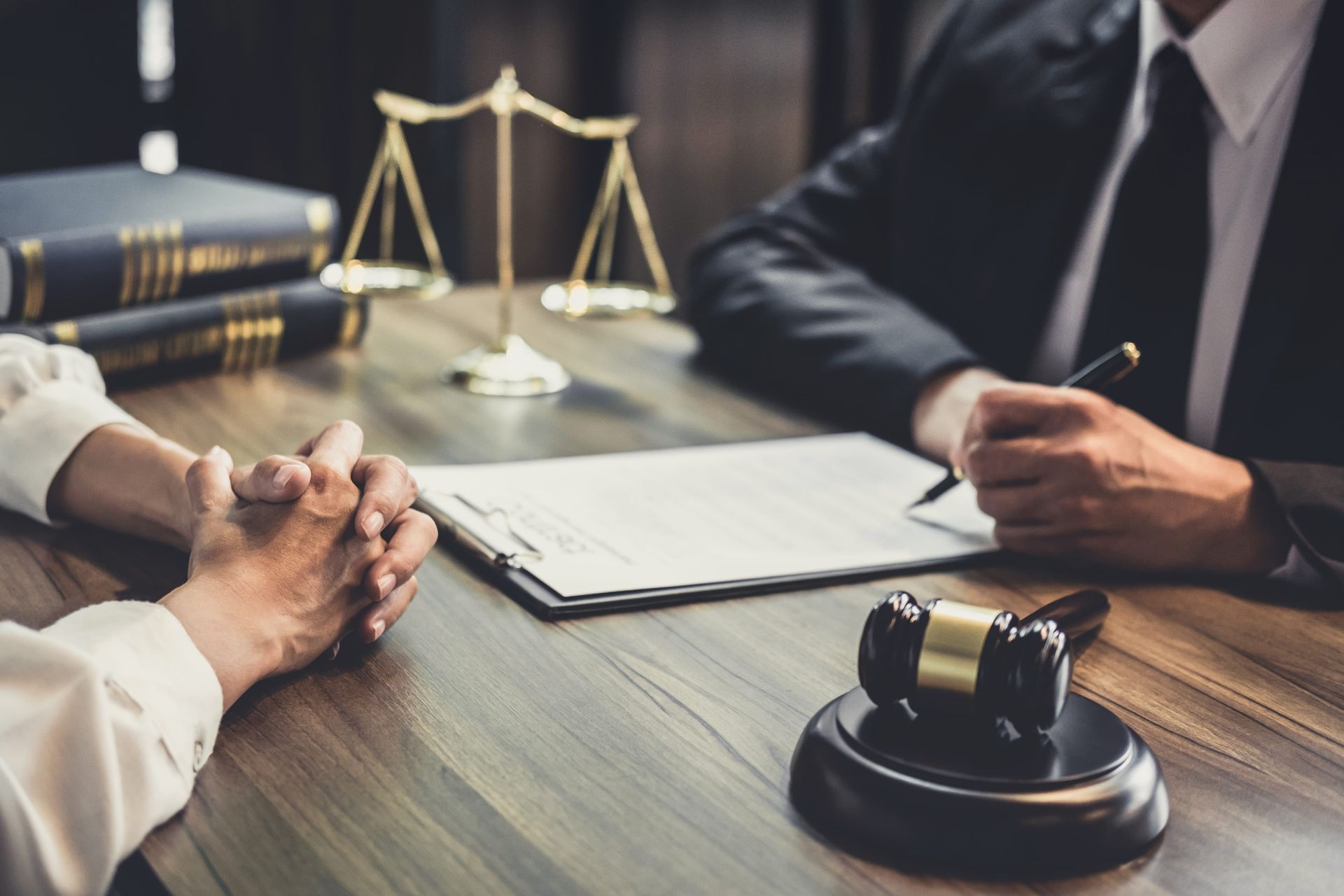 Lawyers discussing a case at a desk with a gavel, legal books, and scales of justice