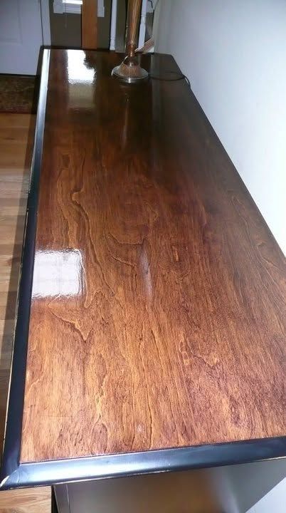 Wooden tabletop with a glossy finish, shown in perspective against a white wall.