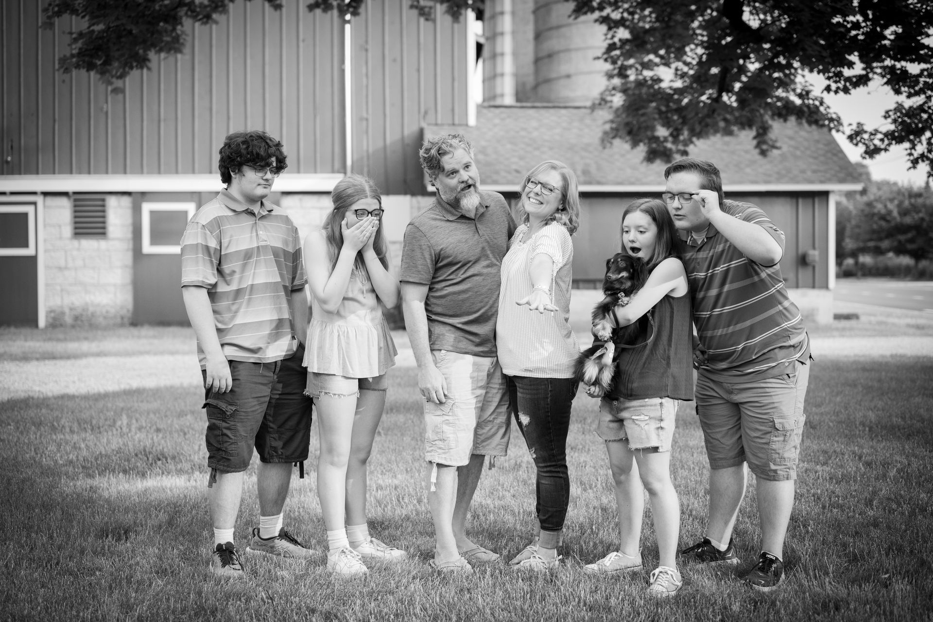 Family poses outdoors, some with playful expressions. A red barn and silo are in the background.