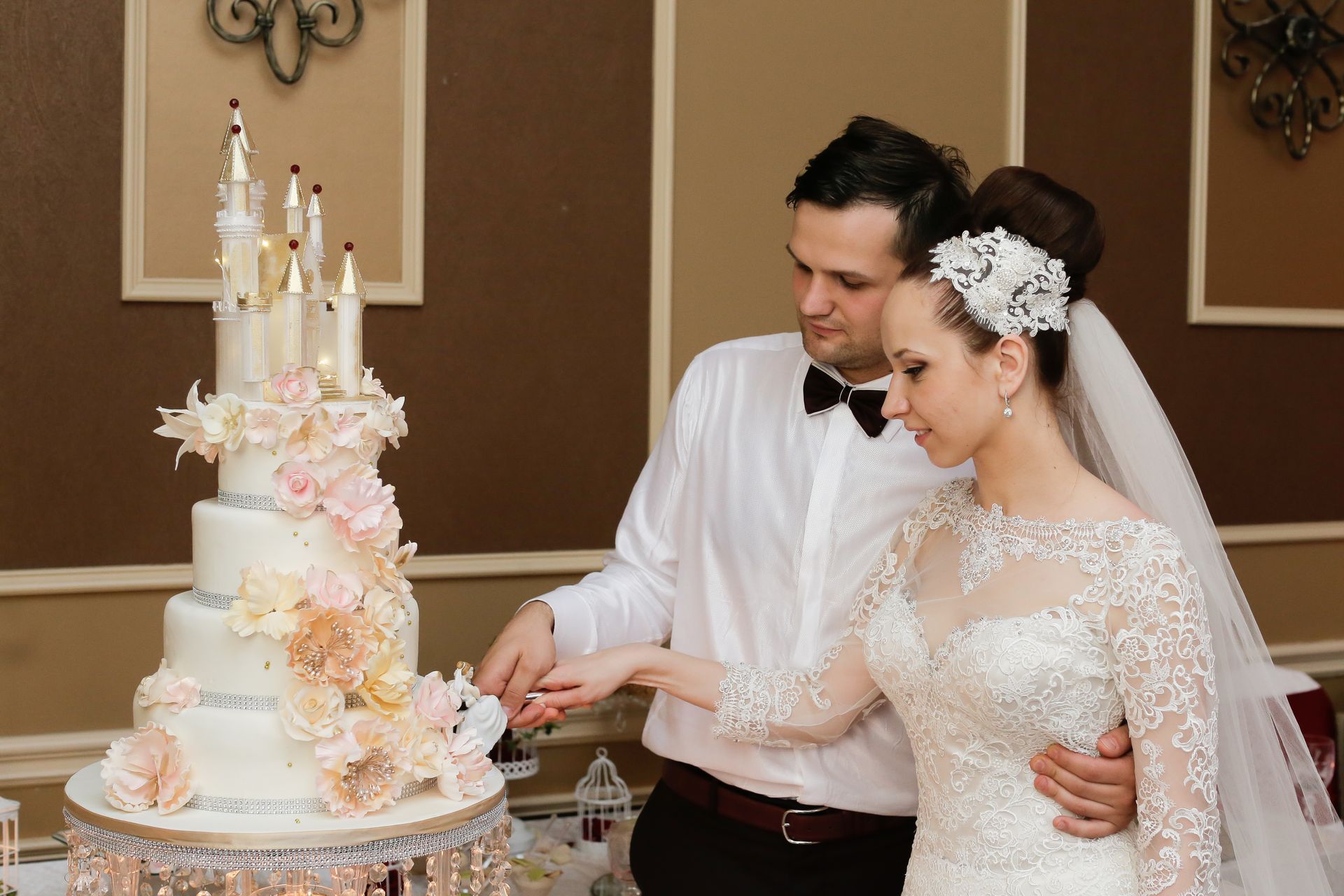 Couple cutting a multi-tiered wedding cake decorated with flowers; elegant setting.
