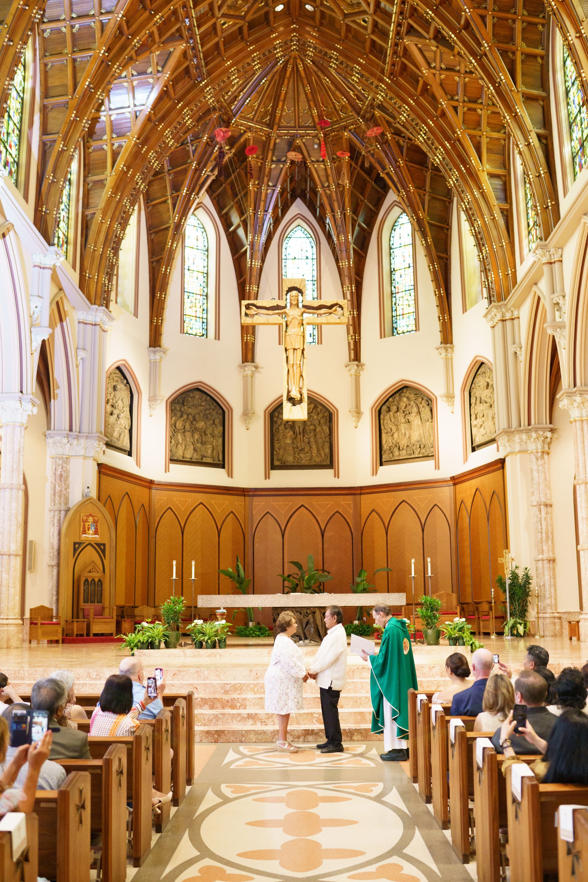 Wedding ceremony in ornate church; couple at altar, priest officiating, guests seated.