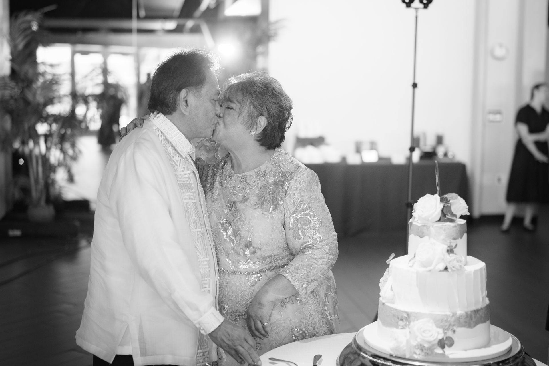 Couple kissing over wedding cake. Elegant setting, decorated cake with floral accents.