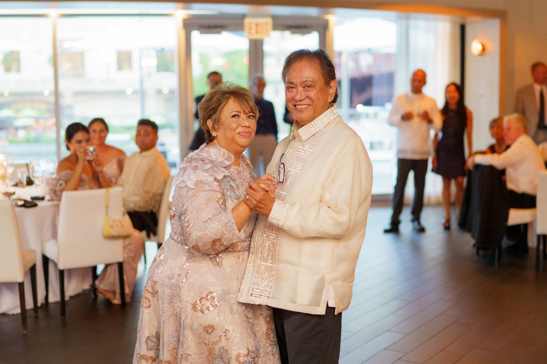 Couple dancing at a wedding reception; indoor setting, smiling, formal attire.