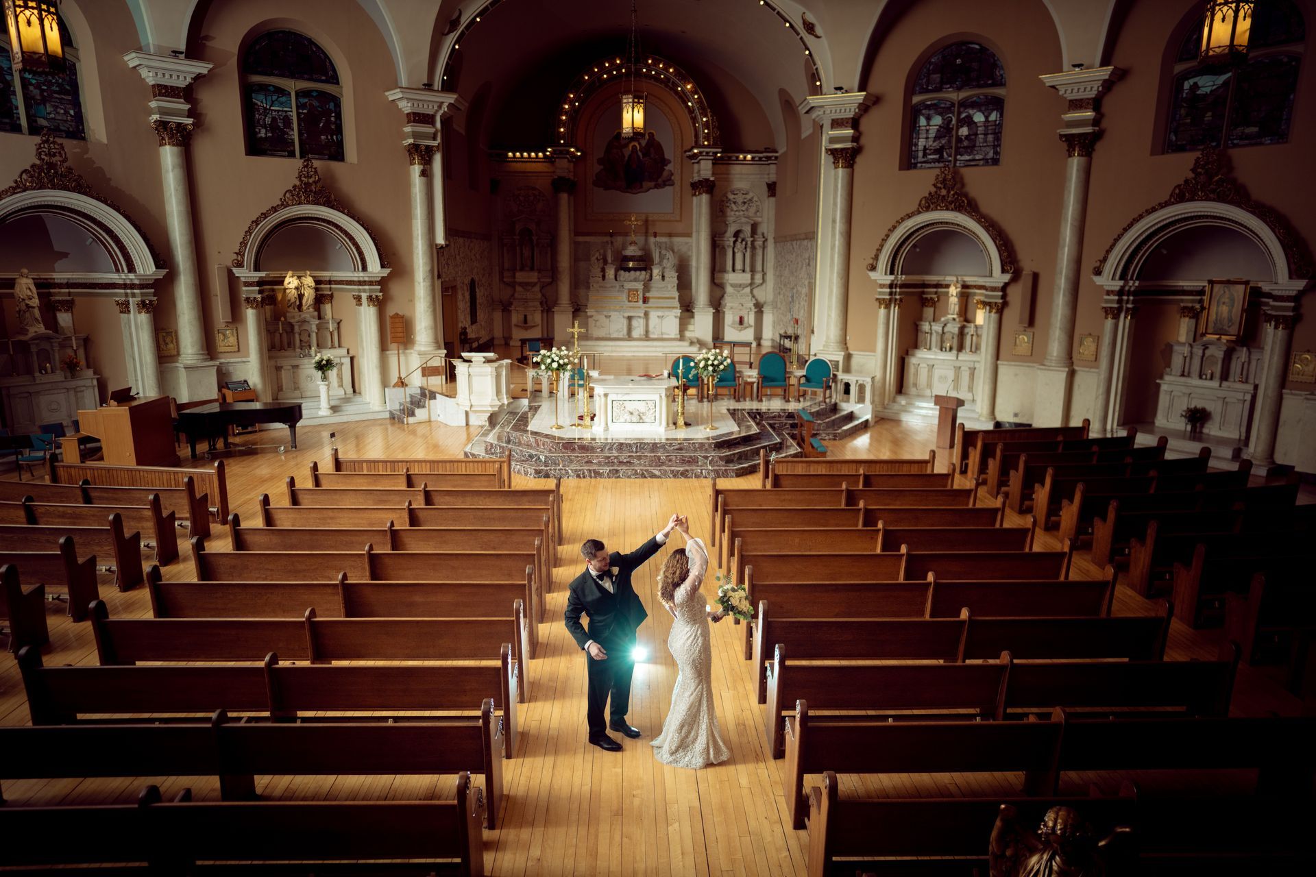 Couple dancing in a church during a wedding; wood pews, altar, and a band in the background.