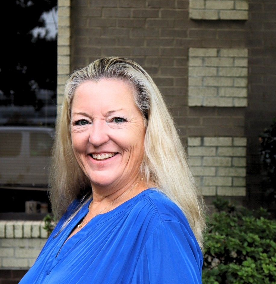 Smiling woman taking a selfie outdoors on a brick patio with white columns in the background