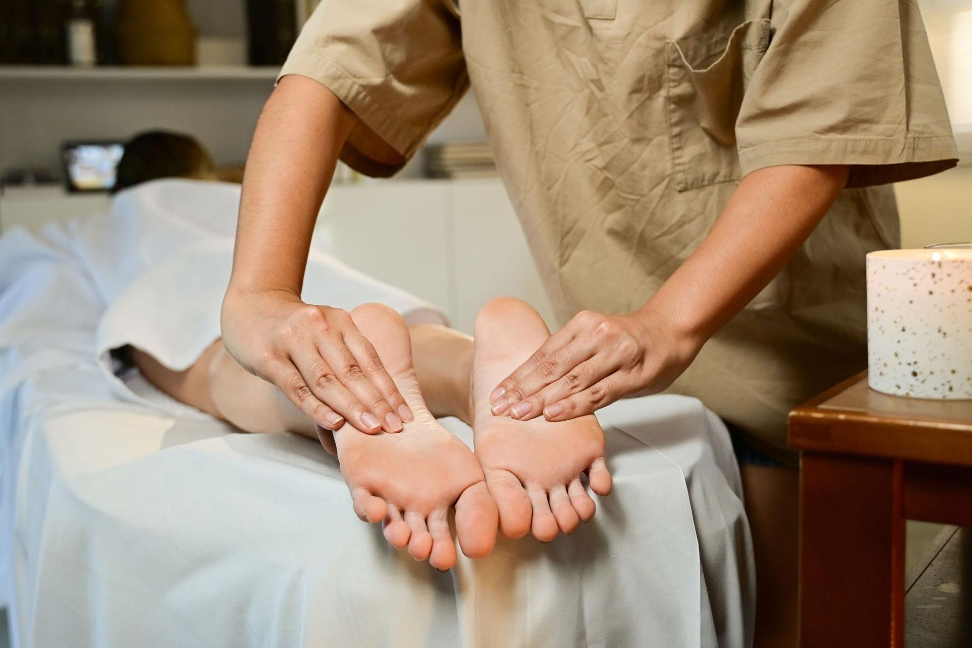 Person giving a foot massage to feet on a massage table in a spa setting