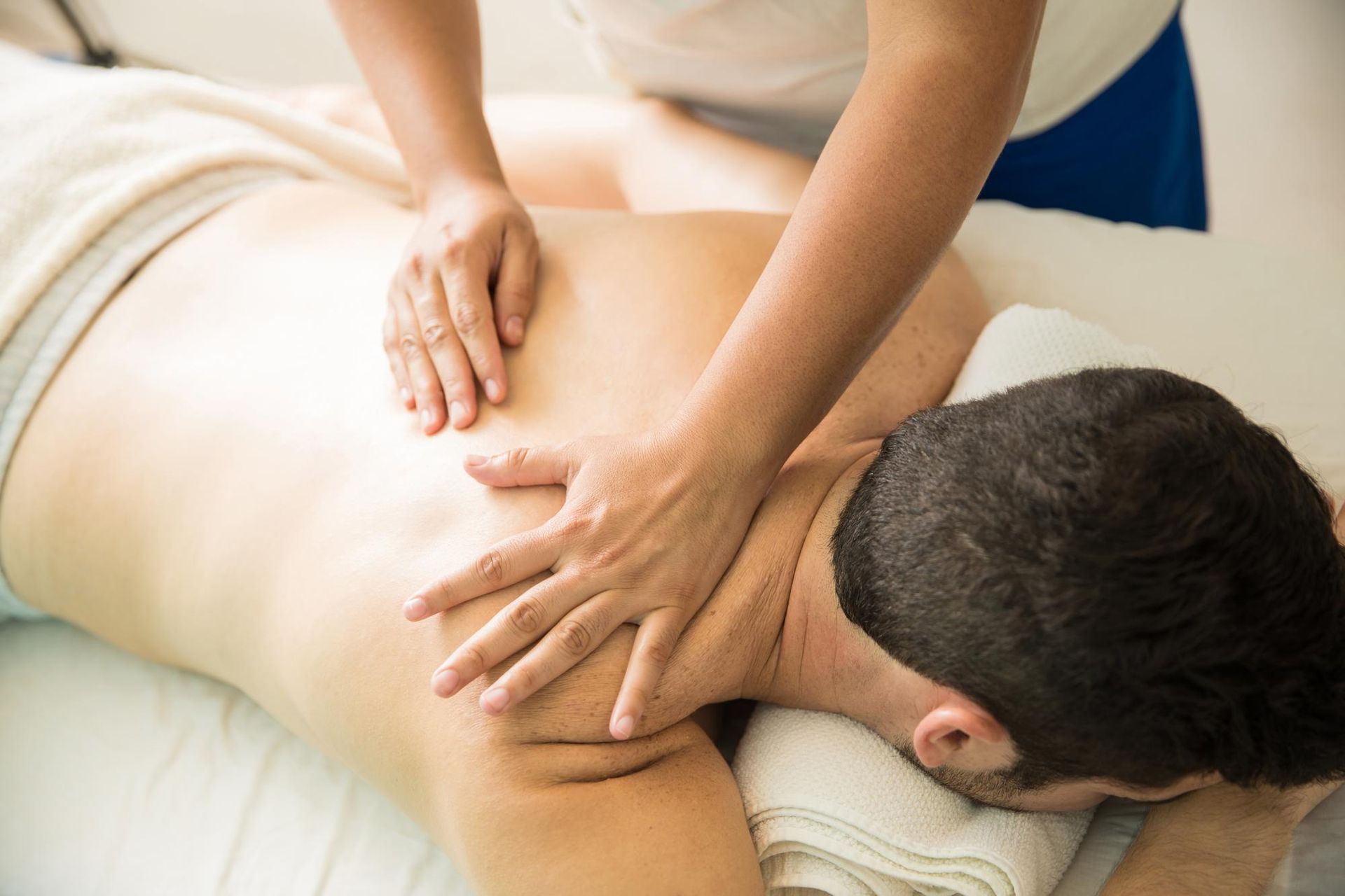 Massage therapist working on a person's back and neck on a treatment table