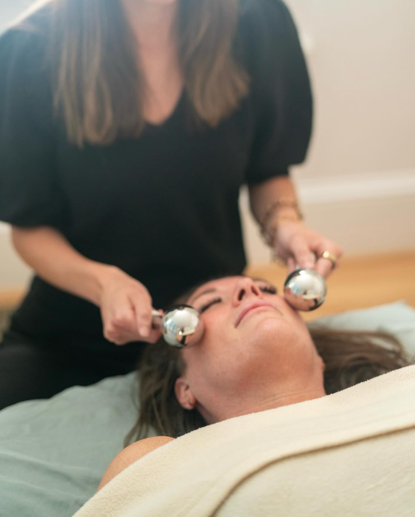 Facial massage with cooling stones on a client lying on a treatment table