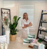 Woman standing in a bright boutique with shelves of candles and packaged goods