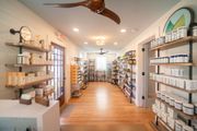 Bright boutique interior with shelves of jars and bottles along a wooden floor aisle