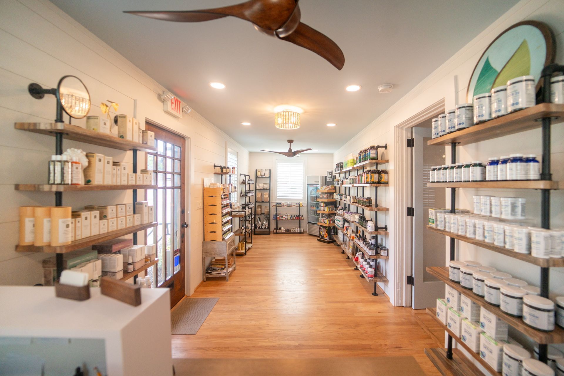 Bright boutique interior with shelves of jars and bottles along a wooden floor aisle