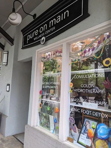 Storefront of “pure on main” wellness clinic with window signs for colon hydrotherapy and detox treatments