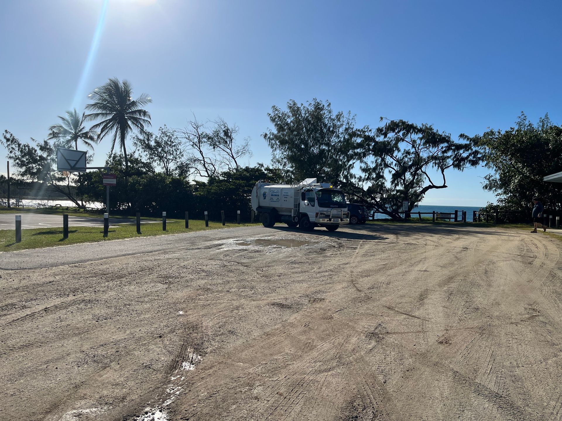 a White Garbage Truck Parked on a Dirt Road Near the Ocean — Blondies Bins in Sarina, QLD