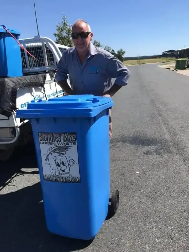 Man Standing Next to a Blue Trash Bin — Blondies Bins in Slade Point, QLD