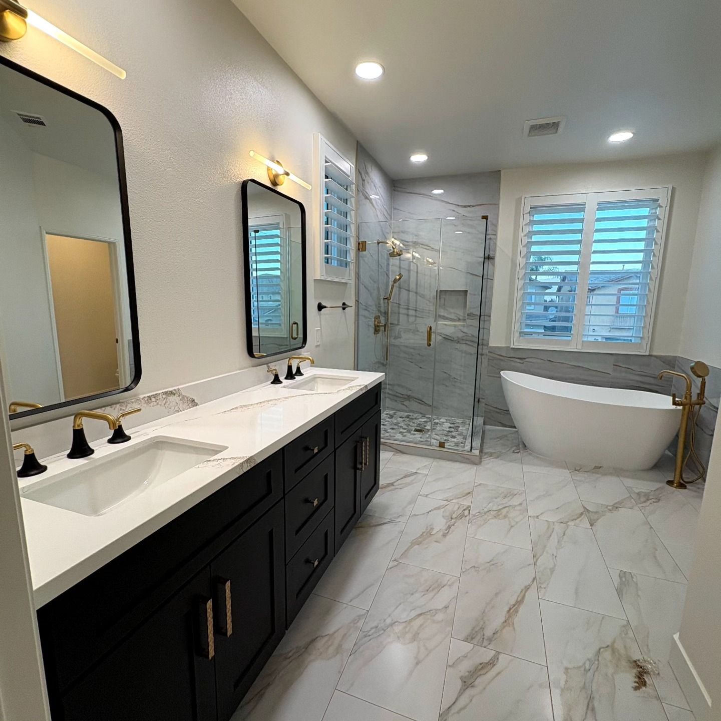 Luxurious modern bathroom with double vanity, glass shower, freestanding tub, and marble tile flooring