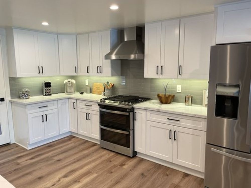 Bright modern white kitchen with stainless steel appliances and light wood floor
