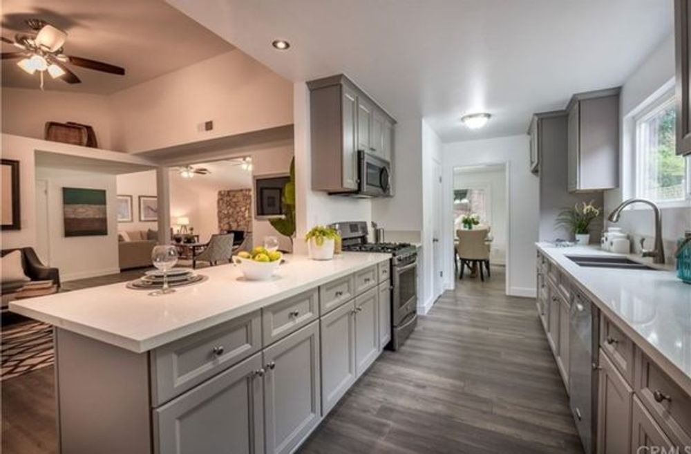 Bright modern kitchen with gray cabinets, white countertops, island, and stainless appliances
