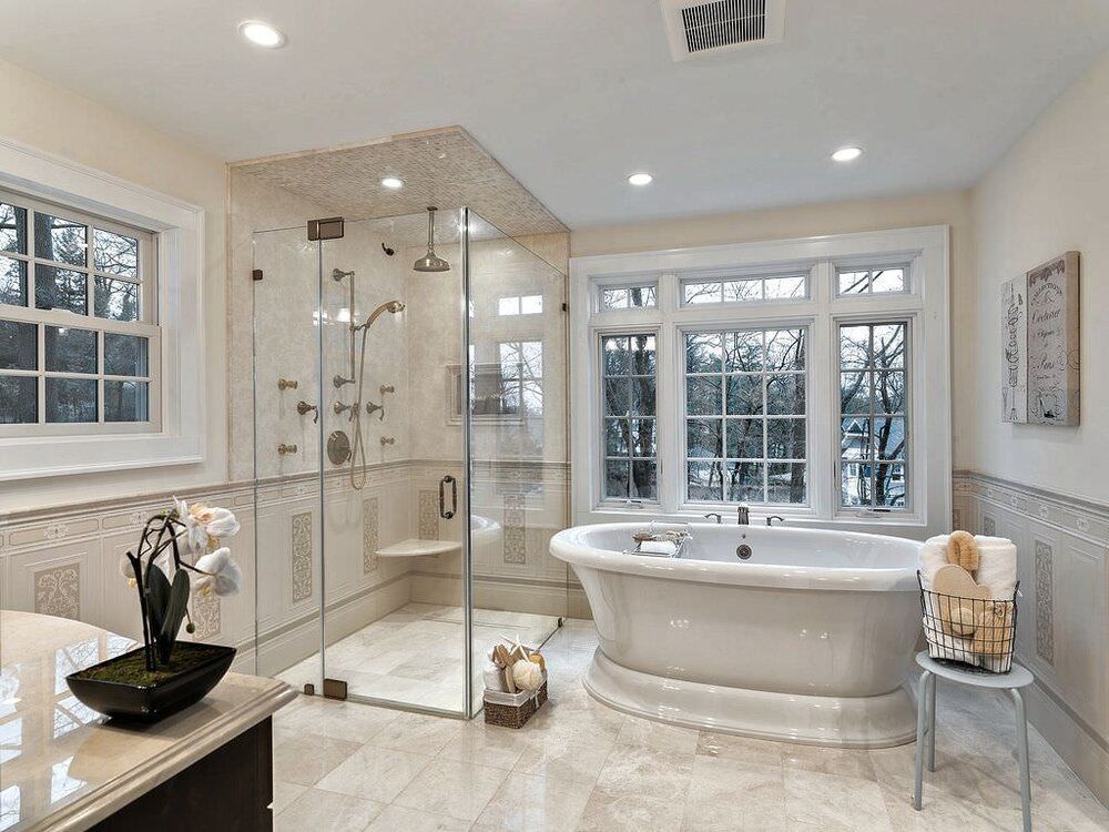 Bright modern bathroom with a glass shower, freestanding tub, and large windows
